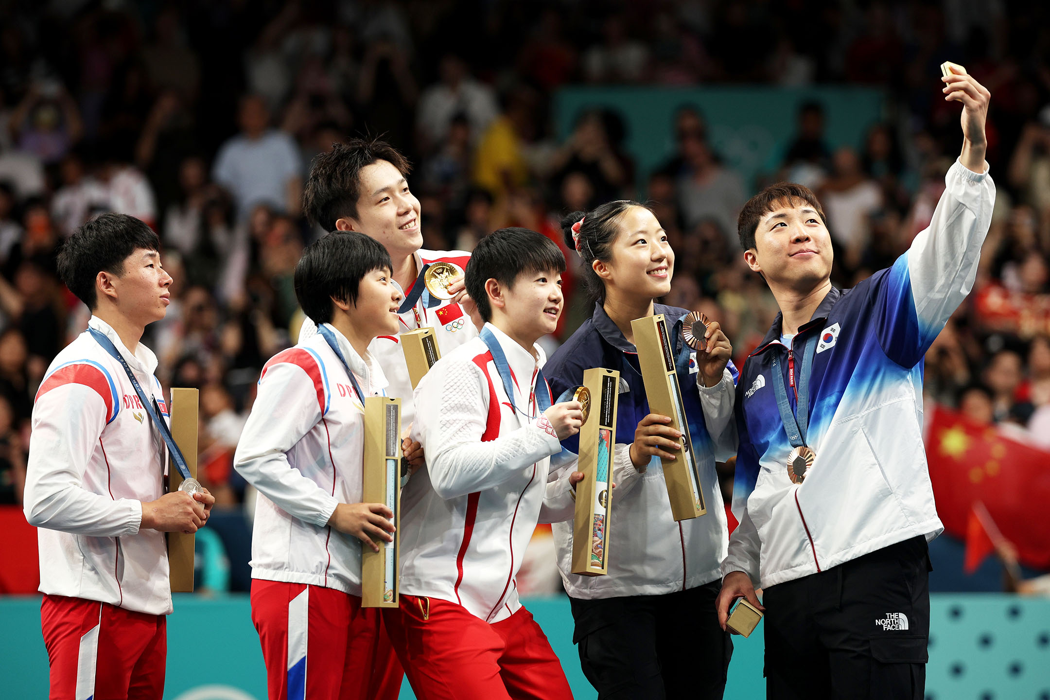 2024年7月30日，法國巴黎，（左起）朝鮮國家隊李鄭息與金琴英、中國隊王楚欽和孫穎莎，以及南韓國家隊林鐘勳、申裕斌合影。攝：Jared C. Tilton/Getty Images