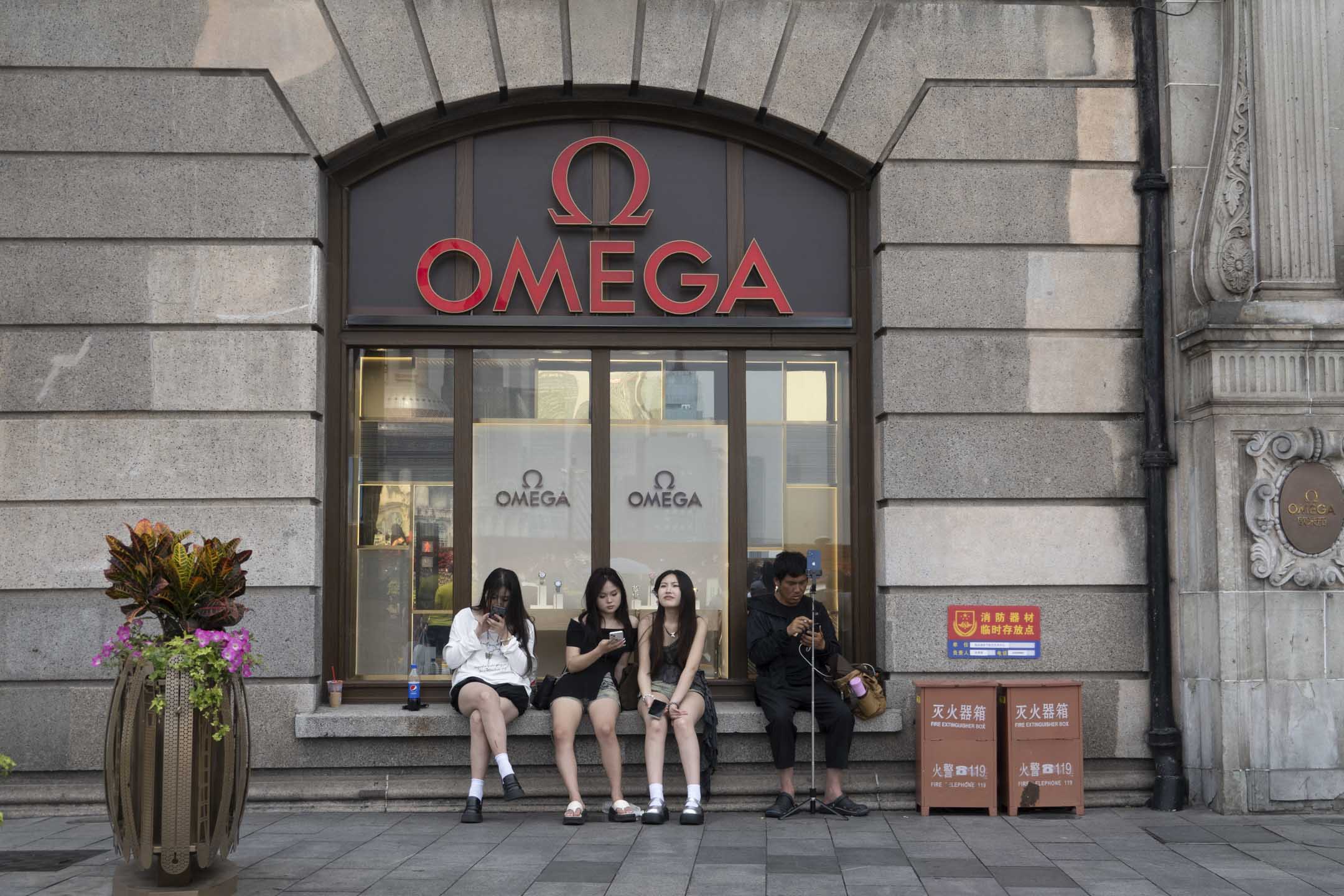 2024年6月4日，中國上海，遊客坐在的 OMEGA 手錶店前。攝：Costfoto/NurPhoto via Getty Images