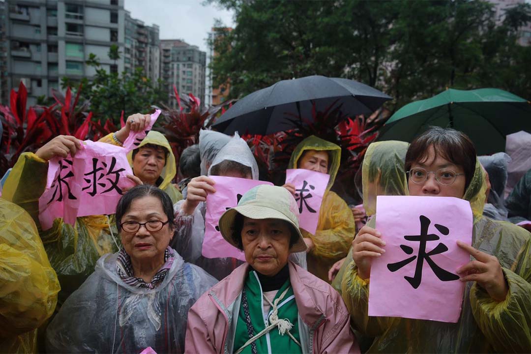 示威者冒雨在场外抗议，现场有警察维持秩序。摄：Billy H.C. Kwok/端传媒