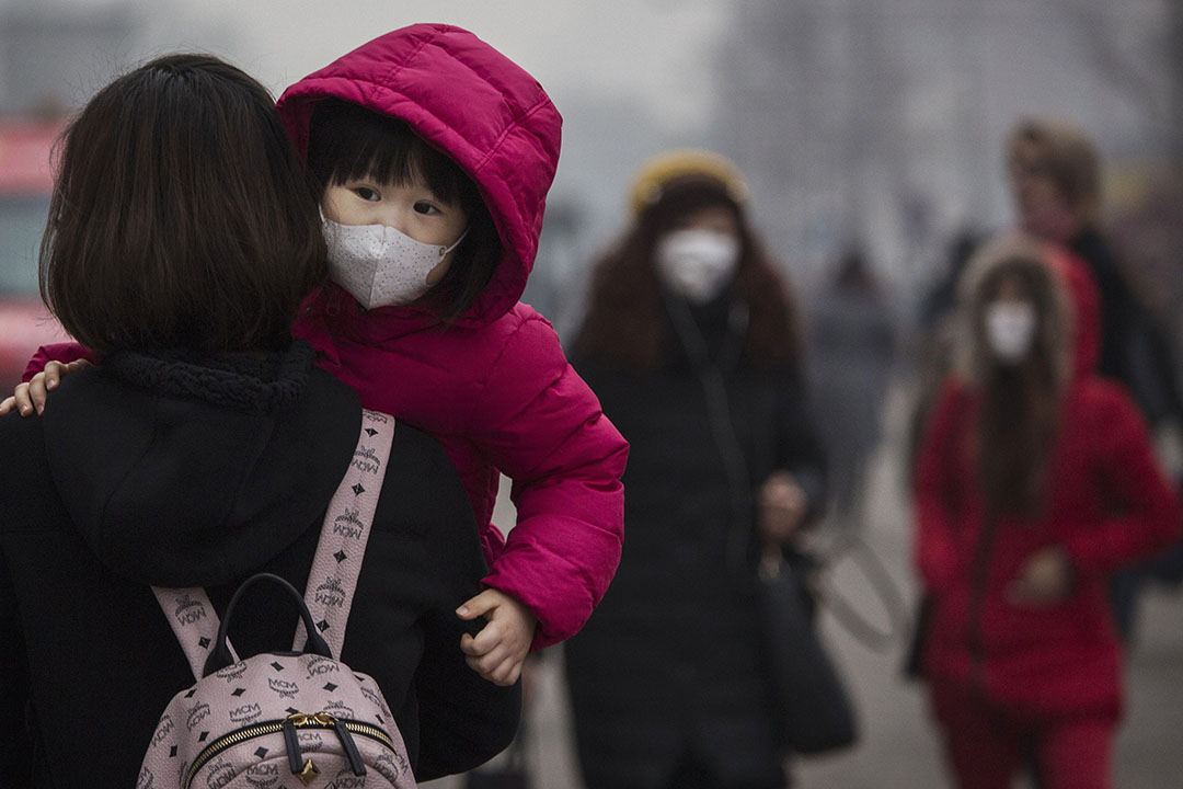 2015年12月8日，北京，一名女童在严重雾霾下戴口罩上街。 摄：Kevin Frayer/GETTY