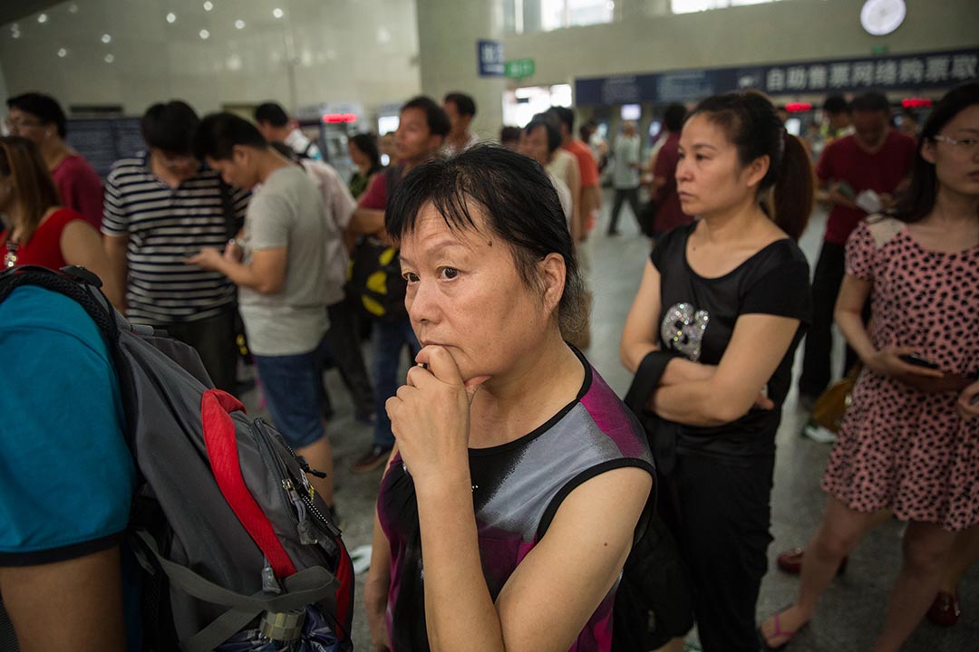 妇女维权人士张玉芬在北京西站购买前往西安的火车票。时常承接取证业务的她，常在全国各地奔波。摄: Jason Jia/端传媒