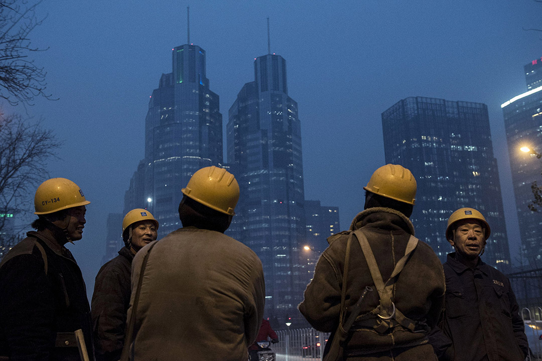 2015年12月9日，北京，工人下班后在地盘附近闲聊。摄：Kevin Frayer/GETTY