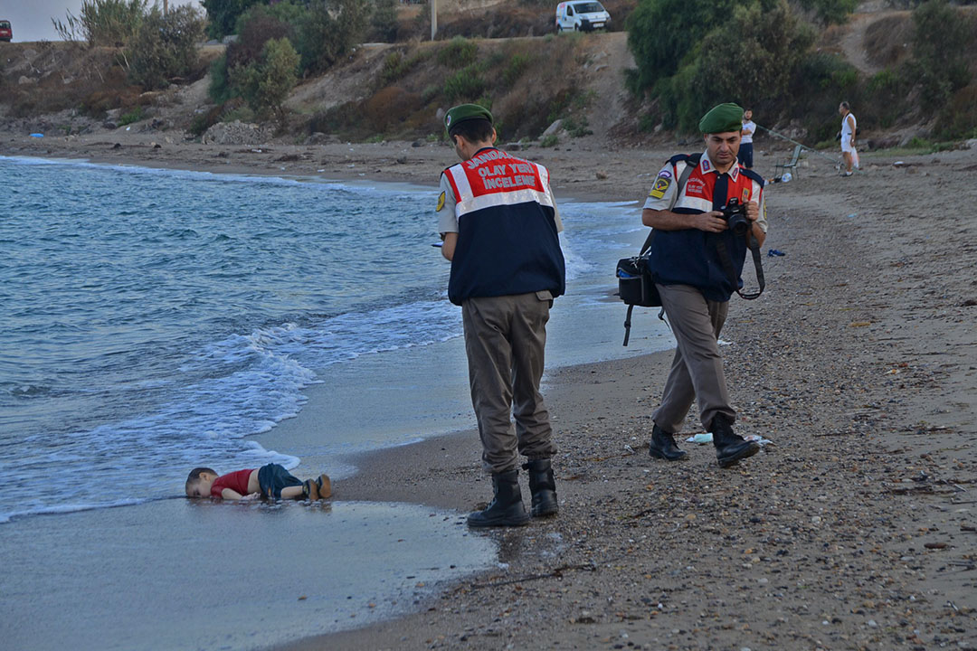 土耳其宪兵在一名溺毙的三岁小童Aylan Kurdi尸体旁调查，Aylan Kurdi一家四口登上偷渡船只希望前往欧洲生活，不幸在土耳其对出海洋沉没。Aylan Kurdi和哥哥及母亲一同溺毙，当父亲前往认尸后向传媒表示，家人死去令他打消前往欧洲的念头，准备返回叙利亚。摄：Nilufer Demir/DHA/REUTERS