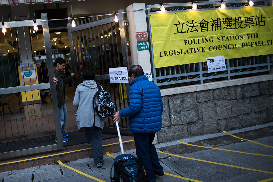 沙田第一城呂明才小學票站的職員在今晨7時半開始投票一刻打開閘門，讓選民進入票站投票。  攝：盧翊銘/端傳媒