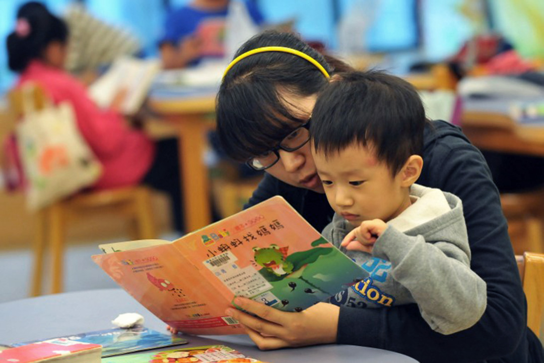 图为一名母亲与孩子在台北国立图书馆阅读图书。摄：Mandy Cheng/AFP