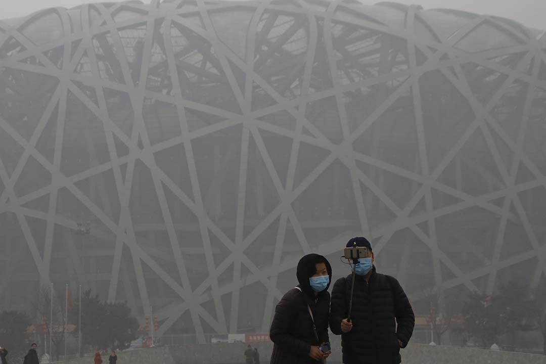 旅客在雾霾笼罩下在鸟巢体育馆前合照。摄：Kim Kyung-Hoon/REUTERS