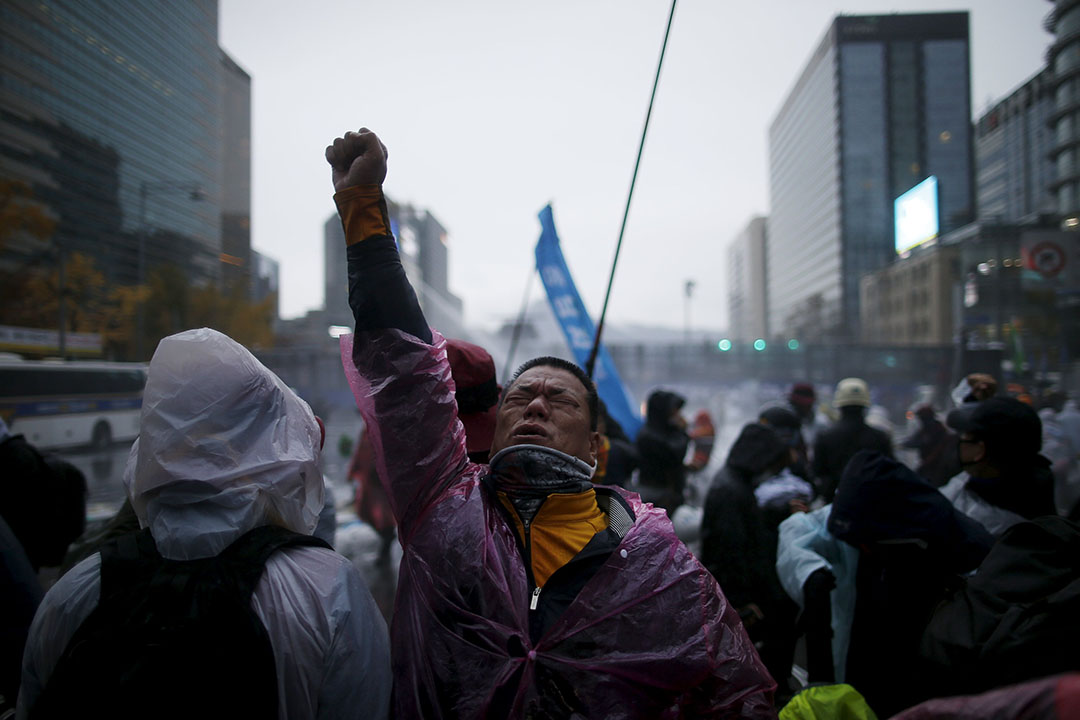 反政府示威者被警方的催淚水劑射中後高舉右手。攝：Kim Hong-Ji/REUTERS