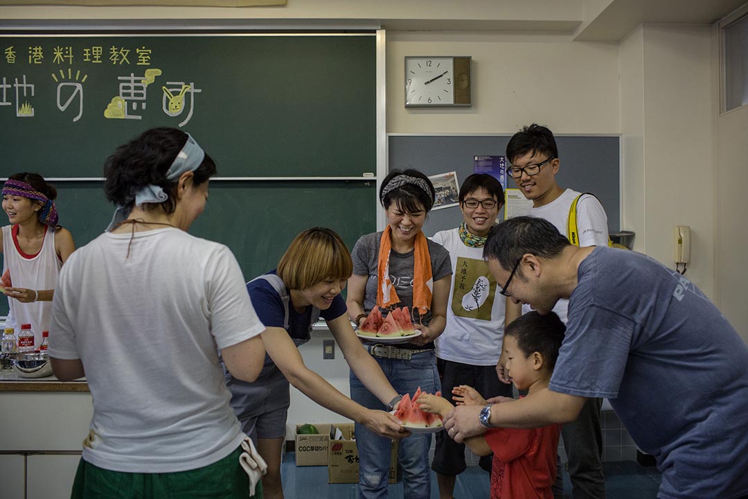 2015年8月23日 日本十日町市 香港農夫在越後妻有大地藝術展中的香港烹調工作坊內派發自己種植的西瓜。攝: Nicole Tung /端傳媒 