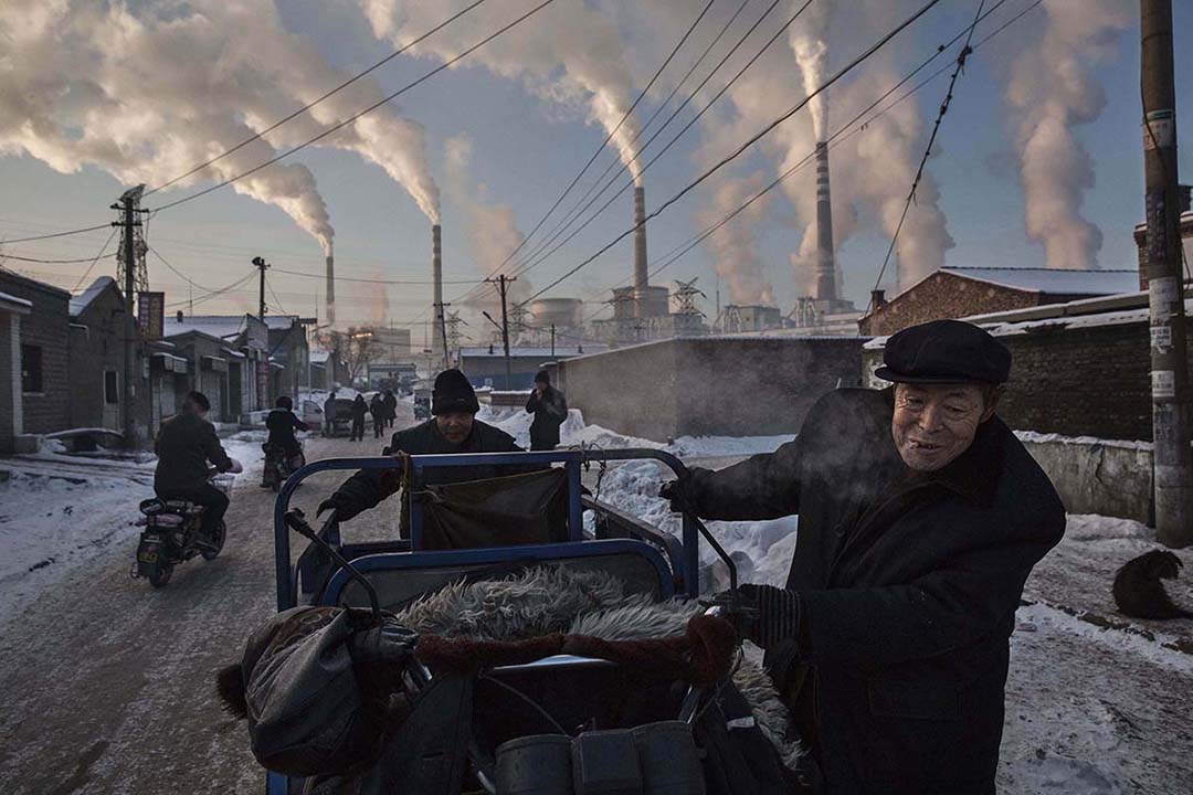 2015年11月26日,中國,兩名男士在一所燃媒工廠附近拉著一輛三輪車。攝:Kevin Frayer/GETTY