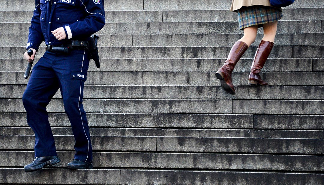 2016年1月9日，德国科隆，一名女性与警察在中央火车站和科隆大教堂之间的楼梯上擦身而过。摄:Sascha Schumann/Getty Images